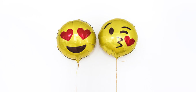Zwei bedruckte Folienluftballons sehen wie Emojis aus.